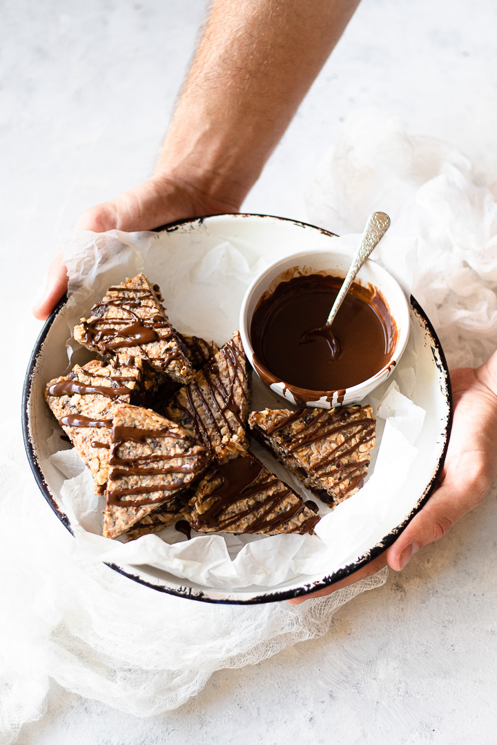 A bowl of chocolate caramel oat triangles drizzled with chocolate