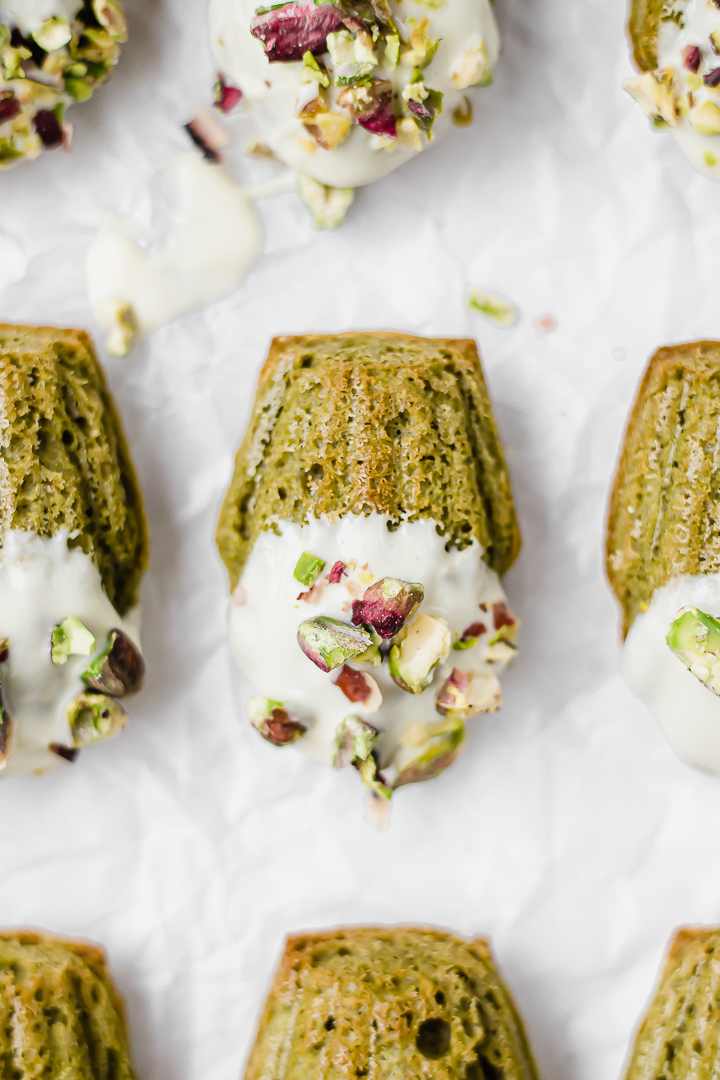 Matcha flavoured, shell-shaped sponge cakes dipped in white chocolate and crushed pistachios