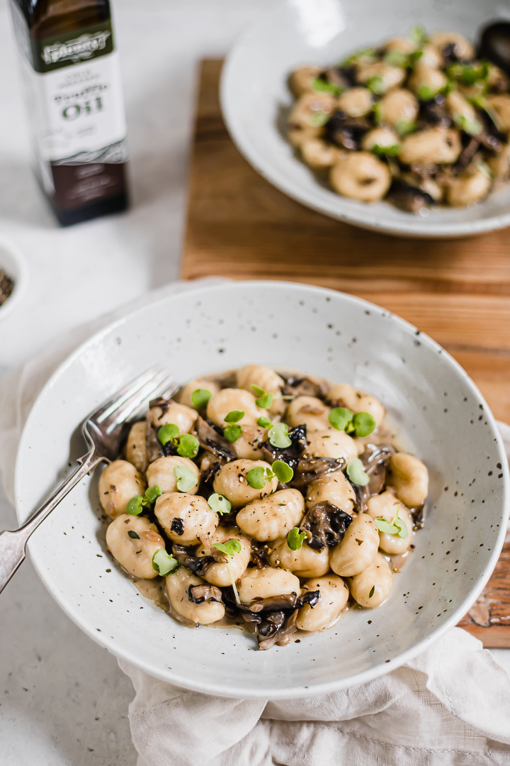 A bowl of mushroom gnocchi with truffle oil and microherbs