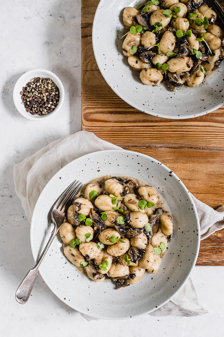 Two bowls of mushroom gnocchi, truffle oil and microherbs.
