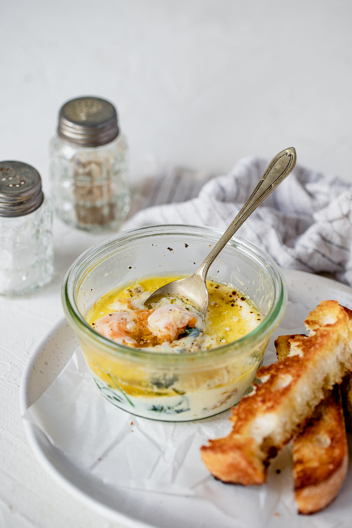 A pot of coddled eggs with a spoon