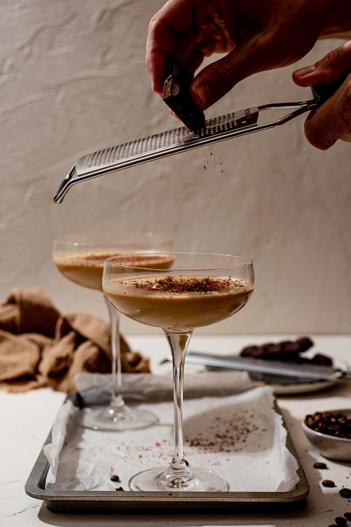 Grating chocolate on top of a tiramisu martini