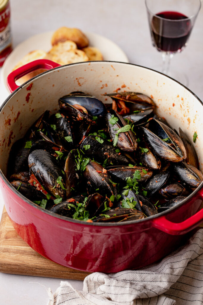 Mussels in a pot with a glass of red wine