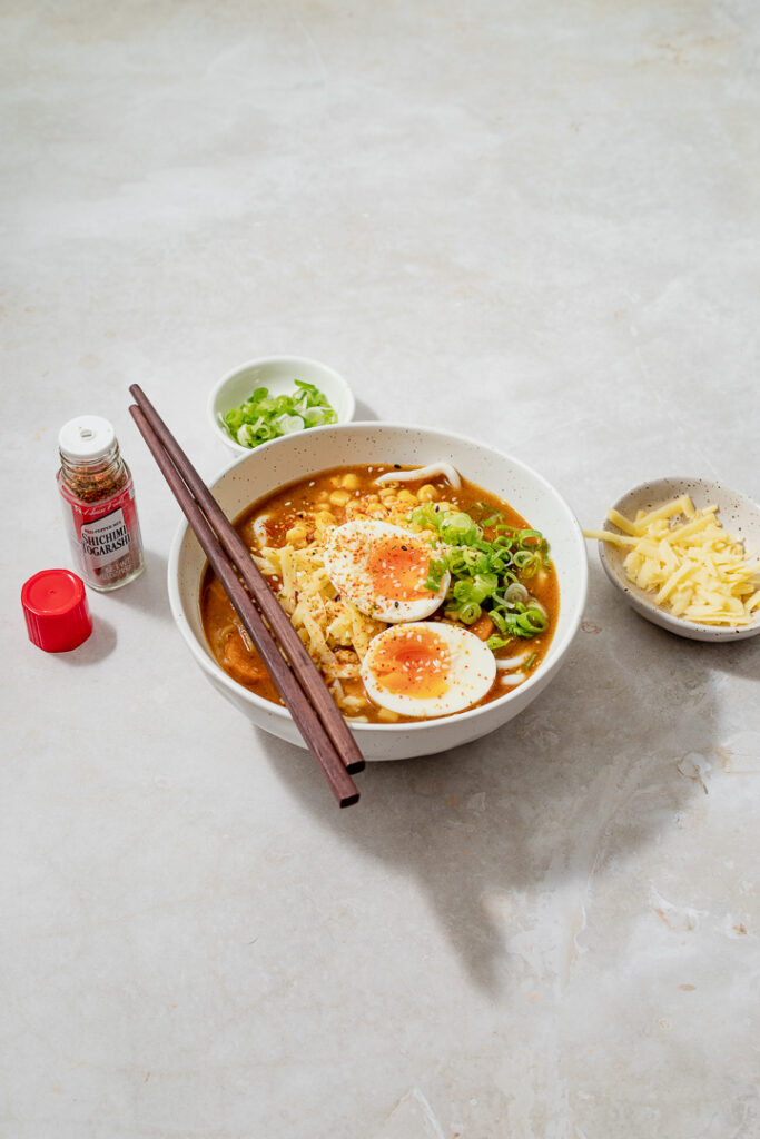 A bowl of curry udon with cheese and spring onions