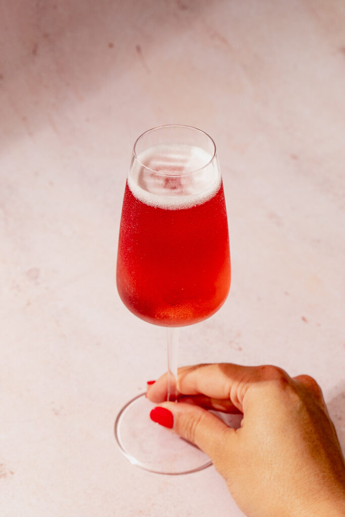 A hand holding a flute of Kir Royale