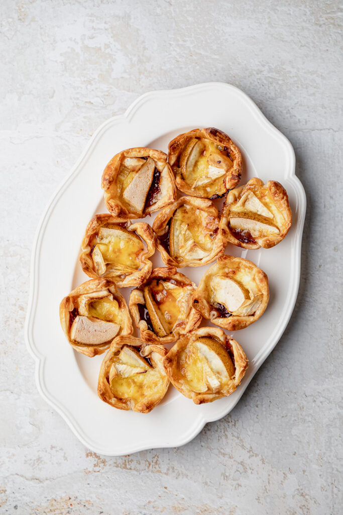 A top down shot of a plate of pear, caramelised onion and brie bites.