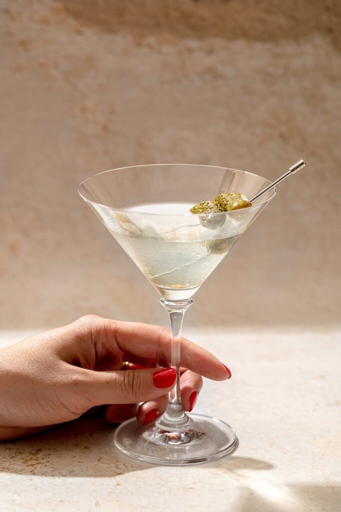 A hand holding a pickle martini