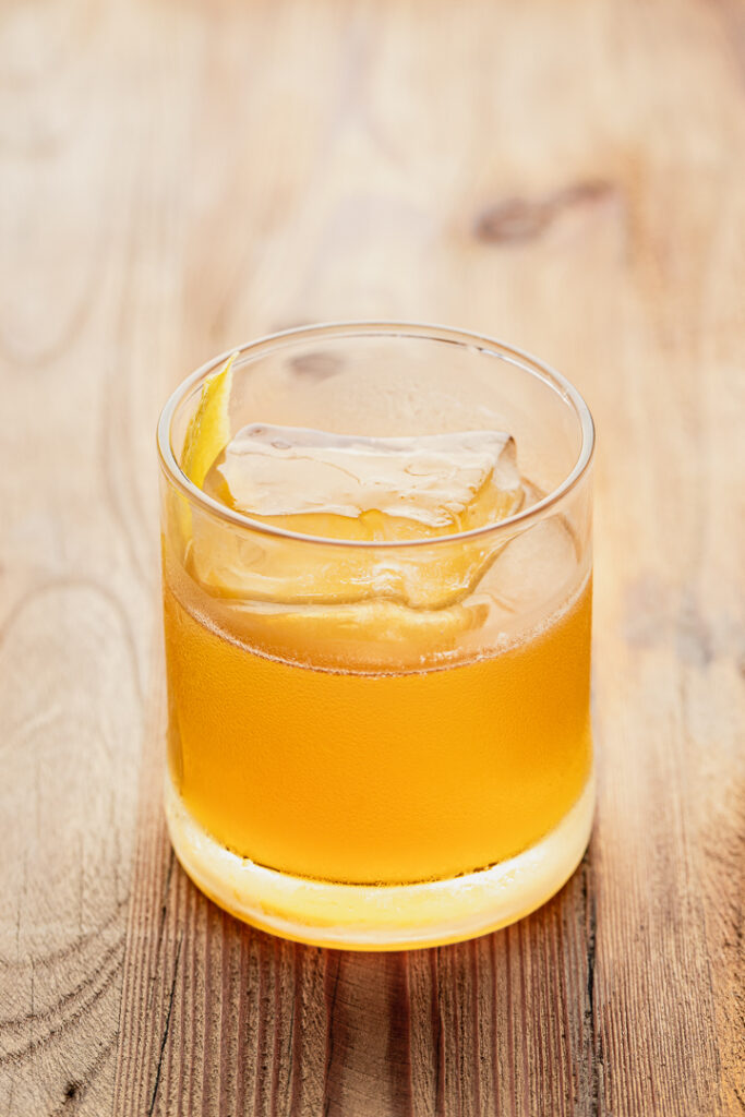 A rocks glass with a golden liquid. The gold rush cocktail