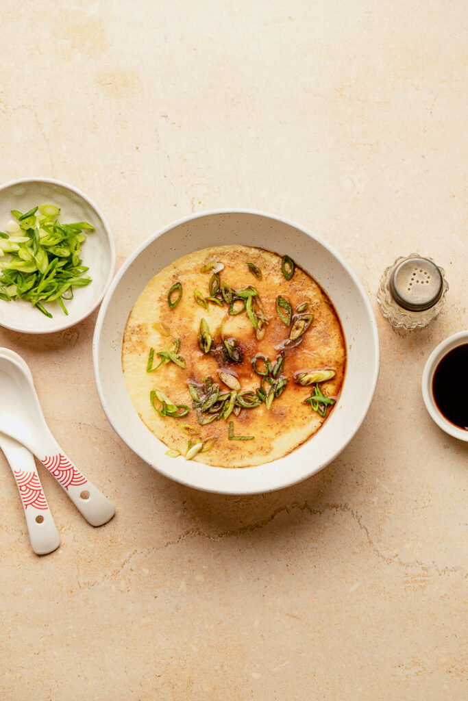 A bowl of savoury steamed egg with condiments surrounding