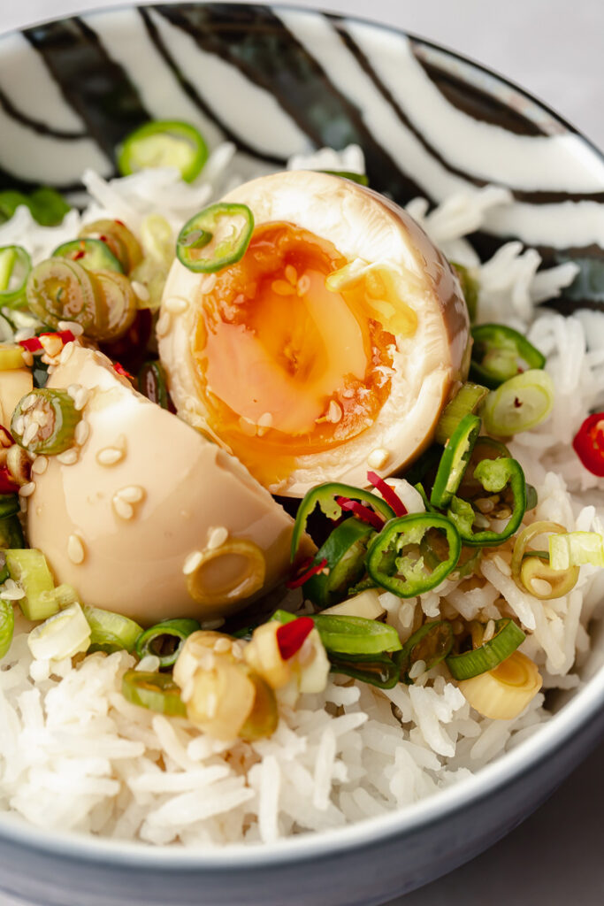 A mayak egg, or Korean marinated egg, cut in half showing a jammy centre sitting on a bed of steamed rice.