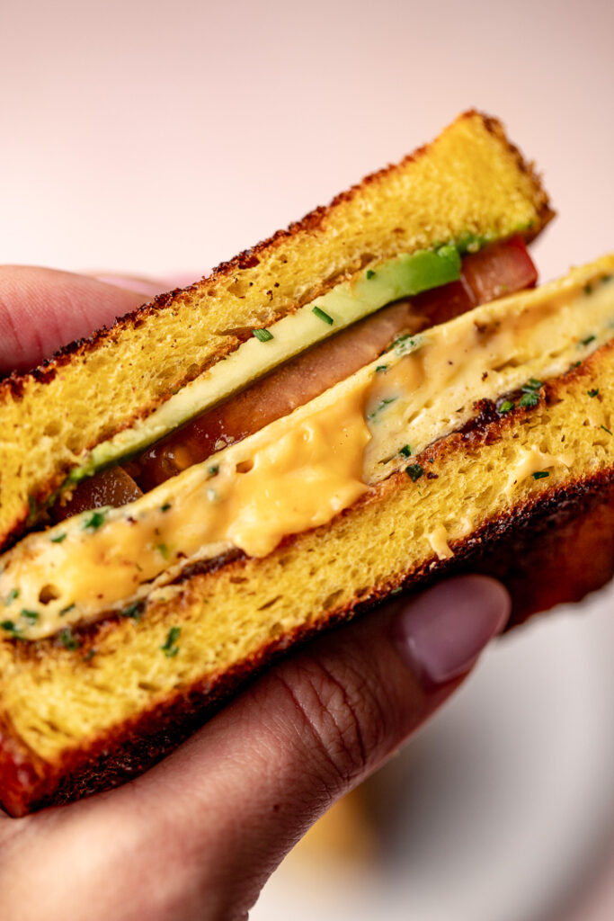 Close up of the cross section of a breakfast sandwich with melted cheese.