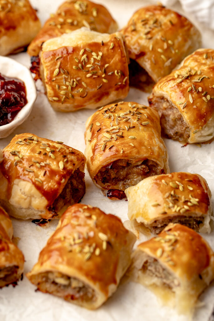 Pork and apple sausage rolls with fennel seeds sprinkled on top of the golden pastry.