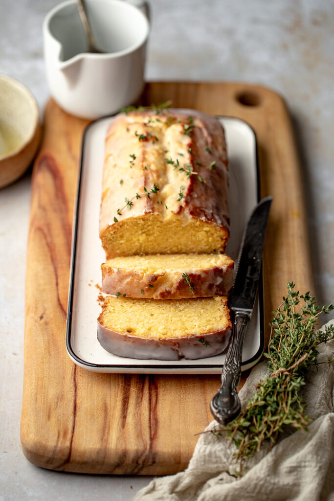 Lemon thyme loaf on a rectangular plate, with two slices cut at the front that are falling foward.