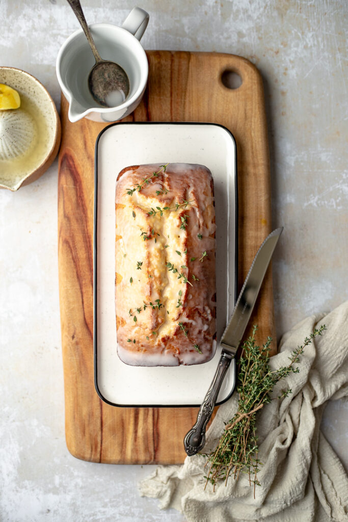 Lemon thyme loaf on a rectangular plate, with a knife resting on the edge.