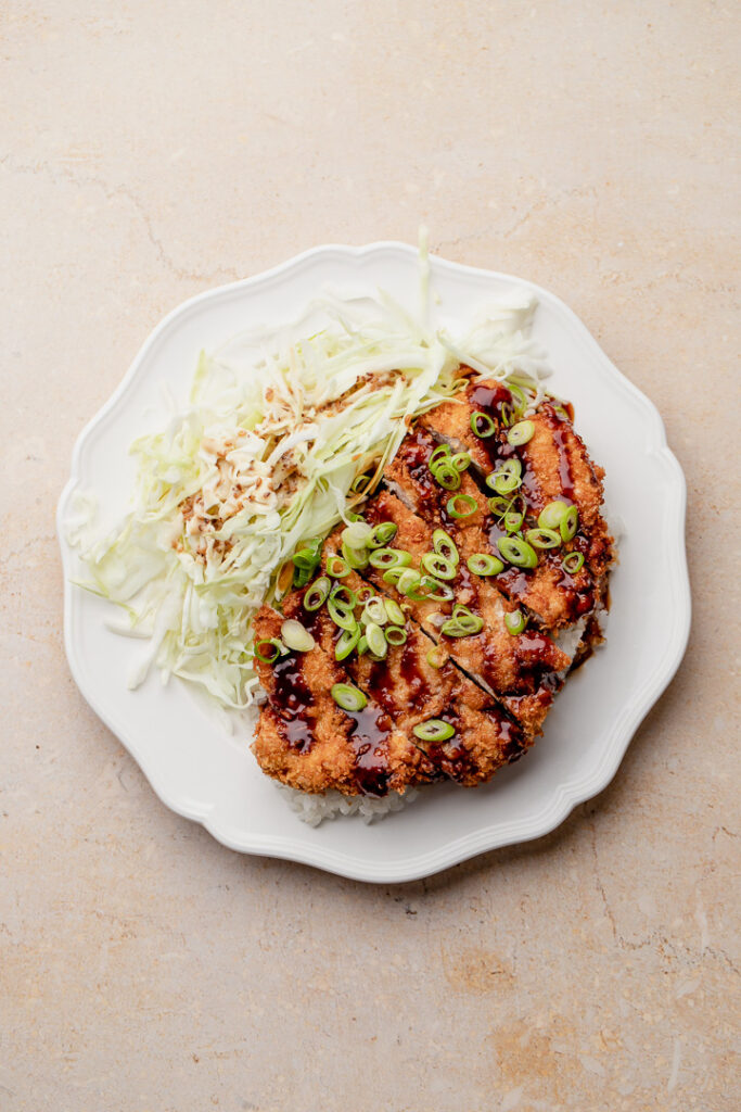 Pork tonkatsu on a bed of rice with cabbage salad on the side.