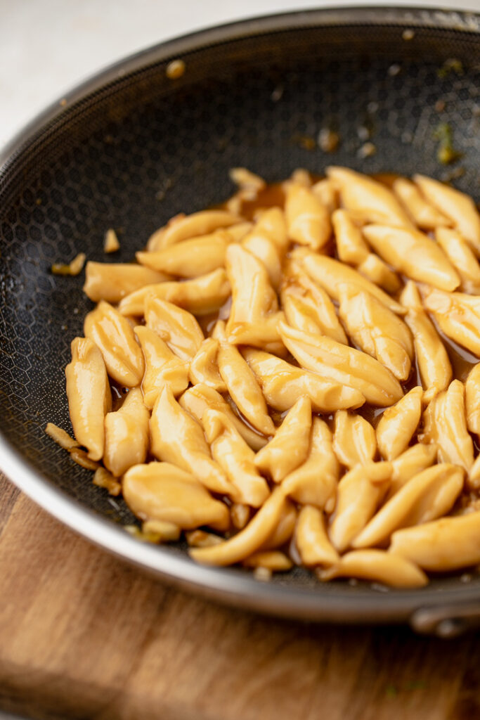 Scissor cut noodles cooked in a sauce, sitting in a fry pan