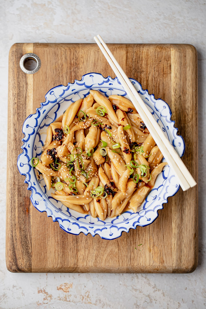 Garlic Oyster Sauce Scissor-Cut Noodles on a blue plate with garnishes and chopsticks