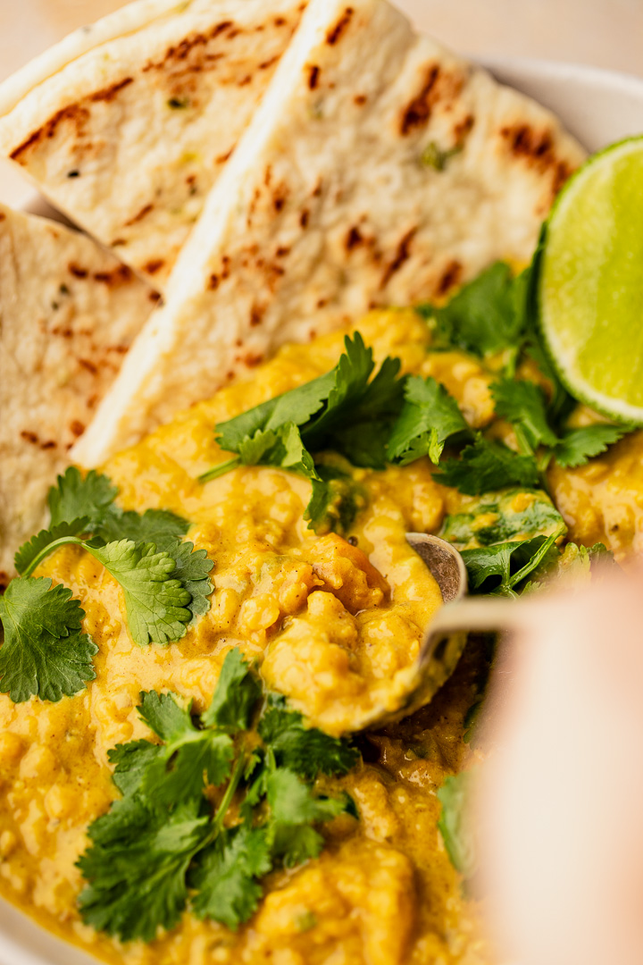 Close up of a spoon scooping pumpkin coconut dal