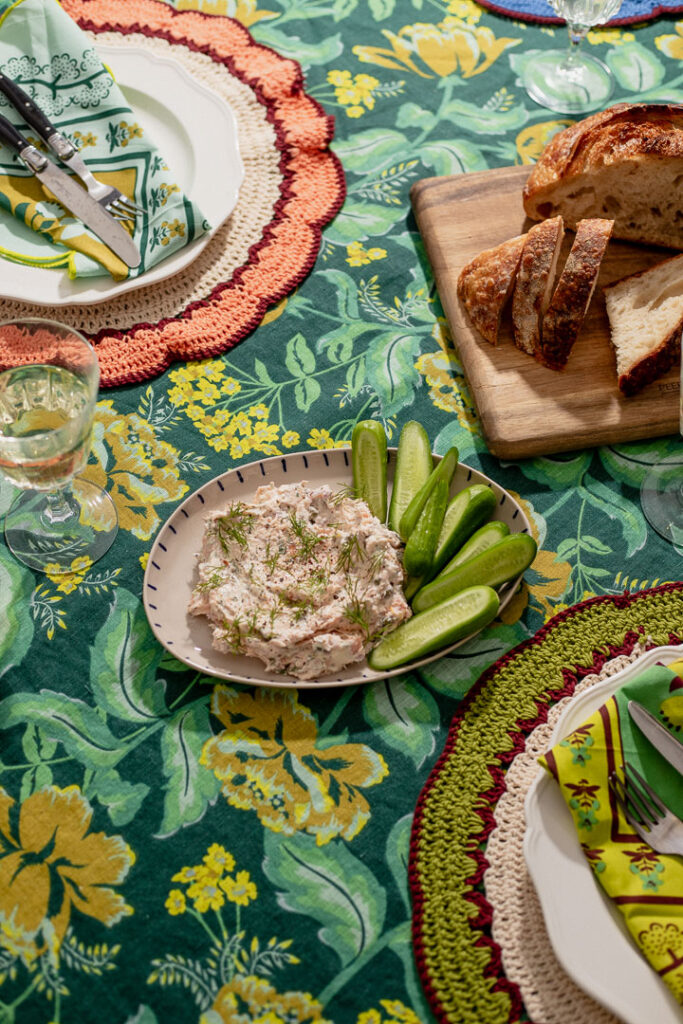 Smoked salmon dip with cucumbers on a colourful green tablecloth.